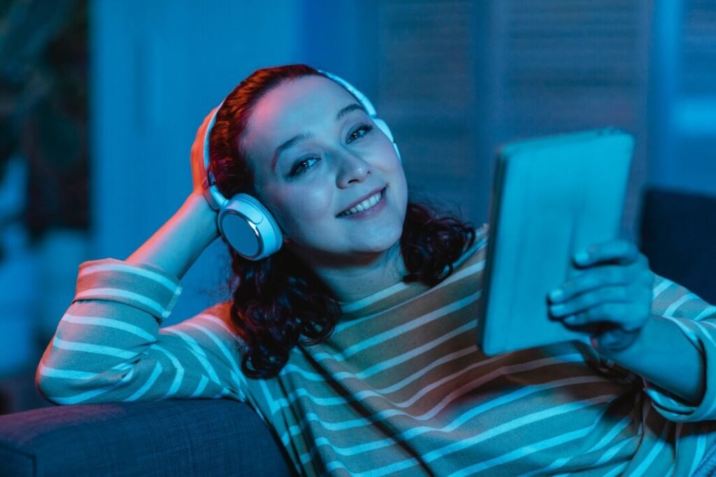 A woman using a tablet with headphones on a sofa at home